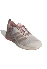 Scarpa sportiva grigia con tomaia in rete, dettagli marroni, suola in gomma e logo a tre strisce. Il design accentuato del tallone presenta ritagli geometrici.