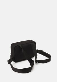 Borsa rettangolare nera con tessuto imbottito, spallacci regolabili e chiusura con zip nella parte superiore. Presenta una superficie testurizzata liscia senza motivi.