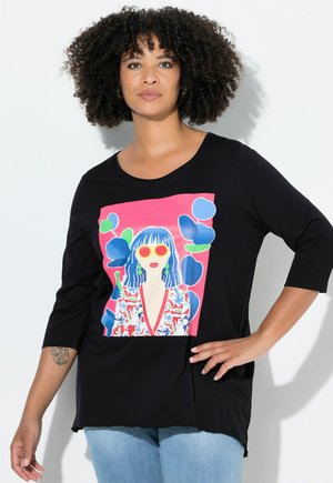 Haut noir à manches longues avec une impression graphique colorée d'une femme portant des lunettes de soleil sur un fond rose, agrémenté d'accents floraux.