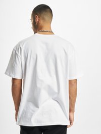 Hvid kortermet T-shirt lavet af bomuld, med en afslappet pasform og et enkelt design uden mønstre. Ryggen har en simpel rund halsudskæring.