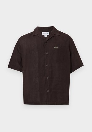 Chemise à manches courtes de couleur marron foncé avec une texture semblable au lin. Elle comporte un col, des boutons sur le devant et un petit logo vert sur la poche poitrine.