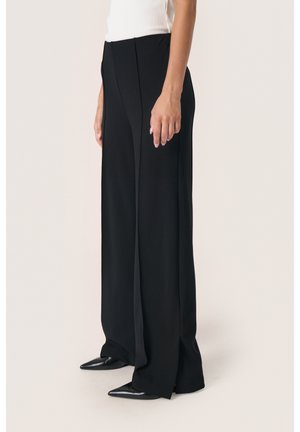 Black wide-leg trousers with a smooth texture, featuring front pleats and a high waist. Paired with pointed black shoes.