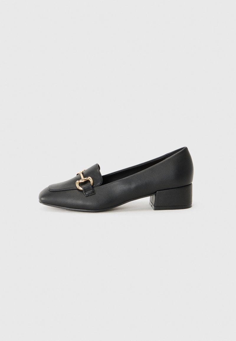 Mocassin noir en cuir à talon bas avec détail mors doré sur un bout carré et talon bloc sur un fond clair uni.