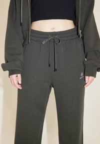 Graue Baumwoll-Sweatpants mit elastischem Bund, Kordelzug und Logo. Der Stoff hat eine weiche Textur und eine lockere Passform.