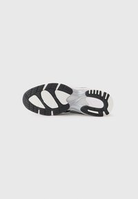 Black and white athletic shoe sole with textured rubber for grip, featuring a honeycomb pattern and cut-out areas for flexibility.