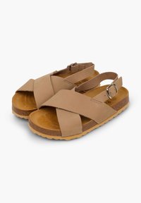 Tan cross-strap sandals feature a textured suede upper and a cork footbed, with a back strap secured by a buckle and a rubber outsole.