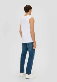 White sleeveless shirt, blue jeans, casual fit. The shirt has a round neckline and the jeans feature back pockets and a straight leg design.