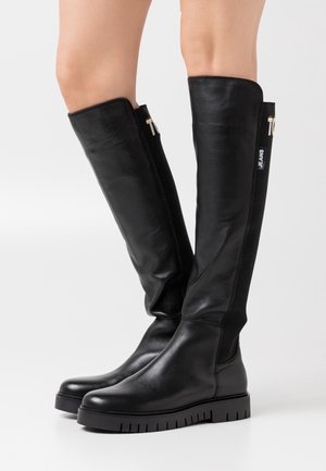 Czarny skórzany botki do kolan o gładkim wykończeniu, elastycznymi bocznymi panelami, grubą gumową podeszwą i akcentami z logo na cholewce.