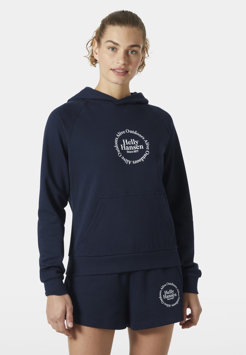 Sudadera navy con un gran logotipo gráfico circular en blanco. Material suave, bolsillo canguro y puños de canalé. Combinada con pantalones cortos navy a juego.