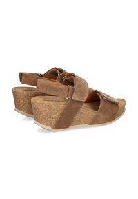 Brown suede wedge sandals with adjustable straps, cork midsole, and a textured rubber outsole, featuring a decorative metal accent.