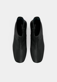 Μαύρα παπούτσια ankle με λεία, ματ δερμάτινη επιφάνεια και ελάχιστες ραφές. Διαθέτουν στρογγυλεμένη μύτη και σχέδιο χωρίς κορδόνια.