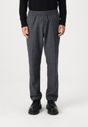 Pantalones grises a cuadros con cinturilla elástica, que presentan un corte relajado y una textura suave, combinados con zapatos negros con cordones.