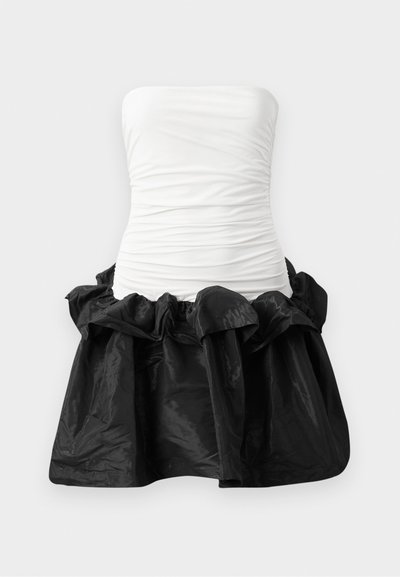 Vestido sin tirantes con un corsé blanco ajustado y textura fruncida, y una falda negra brillante con dobladillo rizado.