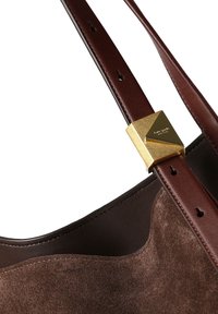 Rjava žametna torbica z obrobo iz temno rjavega usnja. Ima detajl z zlato kovinsko opremo in širok nastavljiv trak z več luknjami.