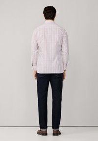 Chemise à manches longues pour hommes avec un motif à carreaux rouge, bleu et blanc ; tissu tissé ; associée à un jean en denim foncé et des chaussures marron.