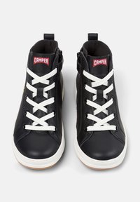 Par med svarte høye lær sneakers med hvite lisser, hvite såler, sidelommer og rødt "Camper"-logo på tungen.