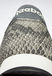 Gros plan sur l'avant d'une chaussure Reebok avec un tissu texturé gris et noir à motif et une languette de talon noire avec le logo blanc Reebok.