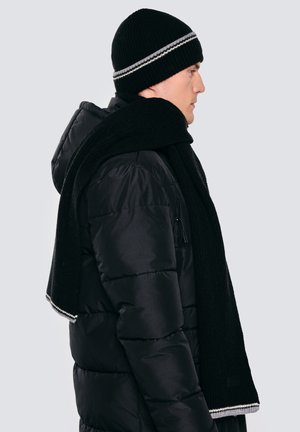 Czarna dziergana czapka z szarym paskiem, do kompletu czarny szalik, noszone z puchową czarną kurtką z kieszenią na zamek po boku.