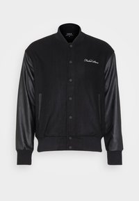 Czarna kurtka bomber z wełnianym korpusem i skórzanymi rękawami, zapinana na napy, z prążkowanym kołnierzem, dołem i mankietami, a także z logo na piersi.