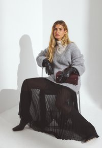 Gray, fuzzy sweater paired with a ribbed, sheer black skirt. Black leather gloves and a maroon handbag with gold accents. Clear background.