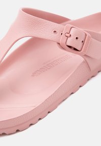 Κοντινό πλάνο ροζ σανδάλι Birkenstock με ρυθμιζόμενο αγκράφα και υφή στην πέλμα σε λευκό φόντο.