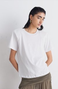 T-shirt bianco in cotone con maniche corte, scollatura rotonda e una vestibilità comoda, abbinato a una gonna verde oliva drappeggiata.