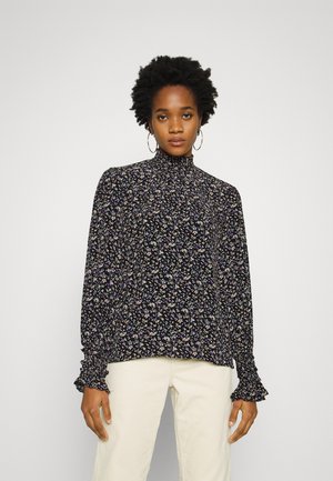 Blusa preta floral com gola alta, mangas longas e punhos franzidos. Apresenta padrões florais multicoloridos em tecido suave.