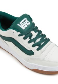 Vans Sneakers aus weißem Leder mit grünen Akzenten, einer strukturierten karamellfarbigen Gummisohle und grünen Schnürsenkeln, gestaltet mit einem klassischen Seitenstreifen.