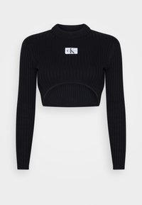 Crop top noir côtelé à manches longues, avec un col arrondi et une découpe à la taille. Comprend un patch logo sur le devant.