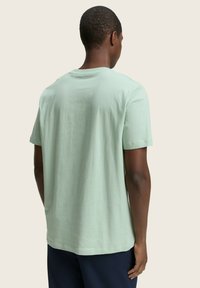 T-shirt verde menta a maniche corte con scollatura a girocollo, vestibilità rilassata e una texture liscia. Design pulito con orlo dritto.