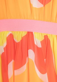Sundress v oranžni, rumeni in rožnati tkanini. Ima teksturiran rožnat pas, tekočo plisirano krilo in abstraktne vzorce. Prosojna material.