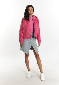 Jachetă roz pufoasă cu design capitonat și glugă, asortată cu un pulover roz texturat și o fustă din denim cu margini desfăcute. Adidașii albi completează ținuta.