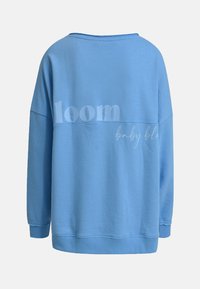 Light blue sweatshirt made of soft fabric, featuring a loose fit, wide neckline, and printed text on the back: "loom baby blo."