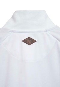 Balta apranga su aukštu apykakle ir mažą rudos spalvos rombo formos odinį ženklelį su stilizuotu logotipu nugaroje, apykaklės zonoje.