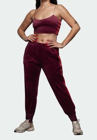 Bourgogne sammet tvådelat set med tunna band och elastisk midja. Avsmalnande byxor har sidfickor och kontrasterande röda ränder.