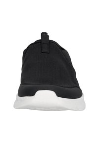 Svart slip-on sko med texturerat mesh-övre och vit gummisula. Har en dragflik på baksidan för enkel på- och avtagning. Minimalistisk design.