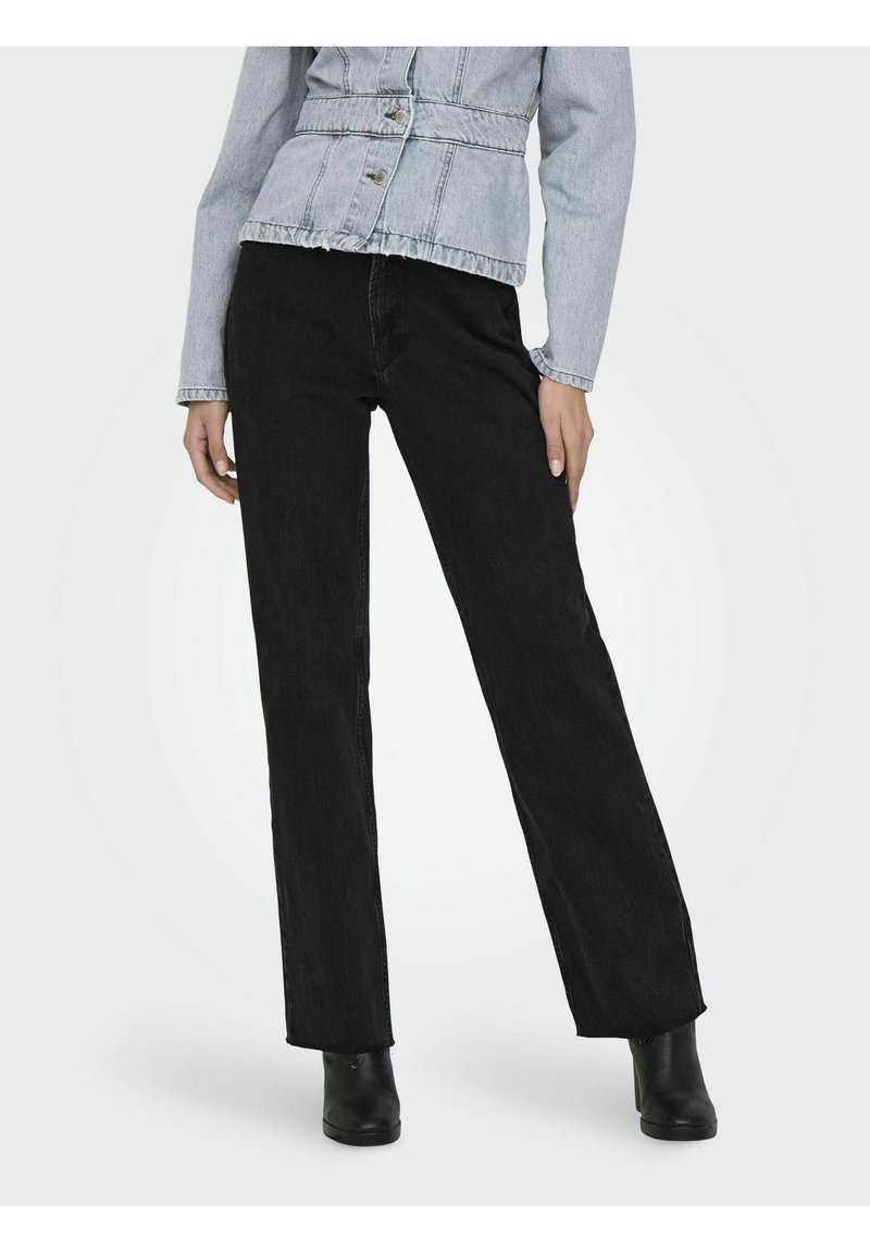 Jeans de mezclilla negros con corte recto, cintura alta y detalles de costura sutiles. Combinados con una chaqueta de mezclilla azul clara y botas negras hasta el tobillo.