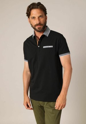 Polo noir avec un col à motif écossais contrastant, patte de boutonnage à trois boutons et une subtile poche poitrine en accent. Manches courtes.