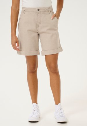 Shorts a righe beige in cotone, con orlo arrotolato, tasche frontali e chiusura con bottone. Abbinati a sneakers alte bianche.