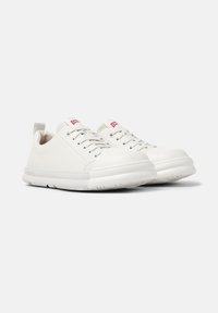 White sneakers with rounded toes and laces, featuring a back tab for easy wear, placed on a neutral background.