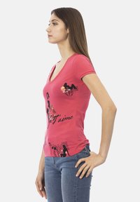 T-shirt rose à col en V avec impression graphique noire et texte "Je t'aime". Manches courtes et design ajusté, associé avec un jean bleu.
