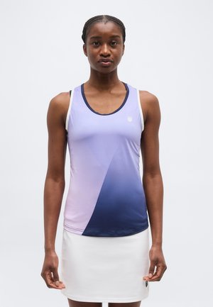 Moteris stovinti, dėvinti be rankovių violetinės spalvos sportinį marškinėlį su perėjimu ir baltą sijoną, priešais paprastą šviesų foną.