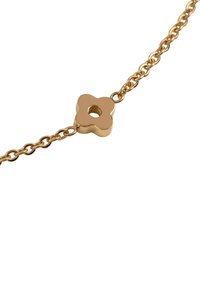 Gold-tone bracelet featuring a flower-shaped central link with a circular cutout, connected by a delicate chain. Smooth texture, elegant design.