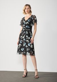 Black floral dress with short, sheer sleeves, featuring blue and white flower patterns, a V-neck, and a gathered waist design.
