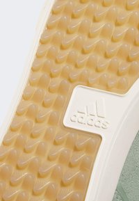 Guma podešev s texturovaným vlnitým vzorem v světle hnědé a krémové barvě, se znatelným bílým logem Adidas embedded.