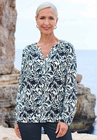 Blusa a maniche lunghe in un motivo astratto blu e bianco, con scollatura a V e dettaglio con bottoni sul collo. Tessuto dalla texture liscia.
