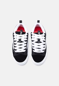 Μαύρα σουέτ αθλητικά παπούτσια με λευκά κορδόνια, κόκκινη επένδυση και λευκή καουτσούκ σόλα· διαθέτουν αντίθετη ραφή και θηλιά στο τακούνι.