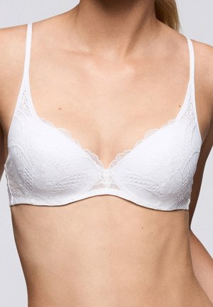 Witte kanten bh met een driehoekige vorm, delicate gegolfde randen en dunne verstelbare bandjes. Zachte stof met een bloemenpatroon.