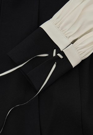 Melnas un baltas garām piedurknēm ar savākto baltu audumu, melnas aproces ar mežģīnēm melnbaltām lentām.