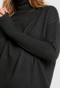 Světle šedý rolák ze žebrovaného úpletu, s dlouhými rukávy a volnějším střihem s jemnou strukturou.